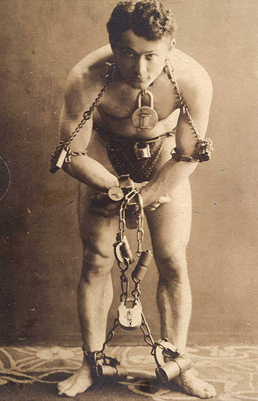 Harry Houdini, full-length portrait in chains.