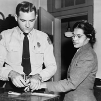 名叫做羅沙‧帕克斯（Rosa Parks）的黑人婦女、在1956年因觸犯「反抵制條款」、在被逮捕後進行按指紋的動作。 Rosa Parks was fingerprinted after a subsequent arrest for violating anti-boycott laws in 1956. 