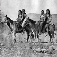 Black and white photo of four Native Americans on two horses
