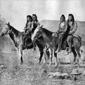 Black and white photo of four Native Americans on two horses