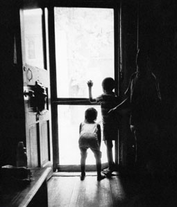 Black and white photo of children looking out an open door