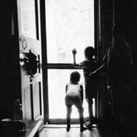 Black and white photo of children looking out an open door