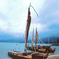 Photo of canoes with sails along shoreline