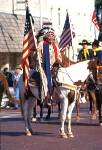 Photo of Chief Charles Little Coyote on horseback carrying an American flag