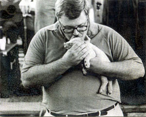 Photo of a man kissing a little pig