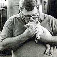Photo of a man kissing a little pig