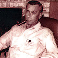 Photo of Max Hunter, sitting in a chair with a pipe