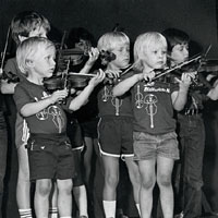Photo of young children playing fiddles on stage