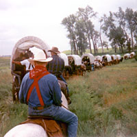 Photo of wagons and riders rounding a bend in the trail