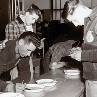 Photo of young men examining grain samples and taking notes