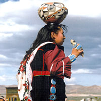 Photo of Zuni Olla woman in traditional clothing with a jar on her head