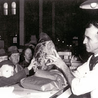 Photo of a man giving a ham over a counter to a young boy