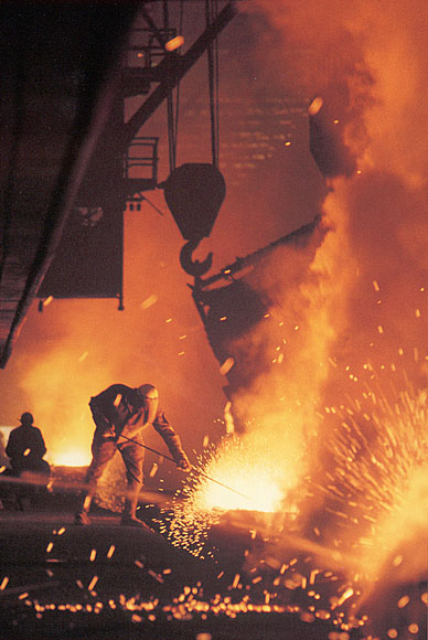 Photo of a person working in a steel mill with sparks flying