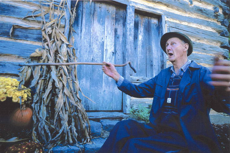 Photo of Ray Hicks telling a story in front of a painted blue structure
