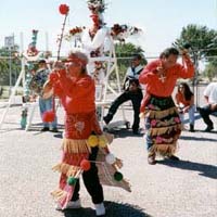 Photo of Los Matachines dancing in front of a cross