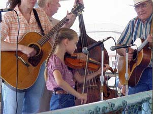 Photo of a young girl playing the fiddle with a two guitarists and a stand-up bass