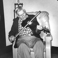 'Henry Reed playing the fiddle in his living room'