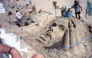 Photo of a sand sculpture of King Neptune's head and hand