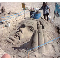 Photo of a sand sculpture of King Neptune's head and hand