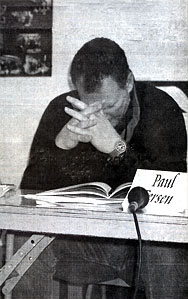 Photo of a man at a table with hands in front of his face and his eyes closed
