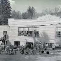 Photo of the front of school with students and teachers posed