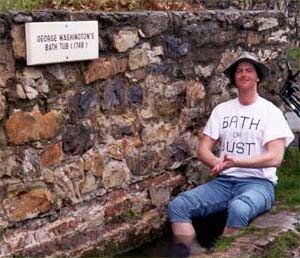 Photo of fully clothed man sitting in outdoor stone tub