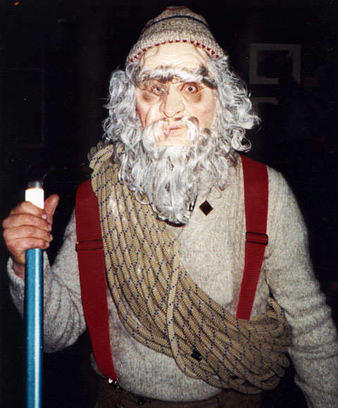 Photo of a person dressed up in a mask, hat, suspenders, and ropes