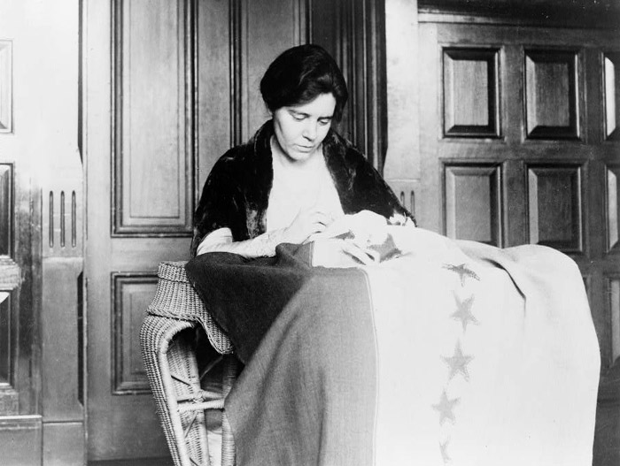 Alice Paul is shown sewing the thirty-sixth star on the suffrage ratification banner.