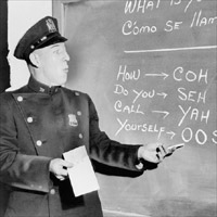 Officer Richard Perry practices basic Spanish phrases using phonetic syllables written on blackboard