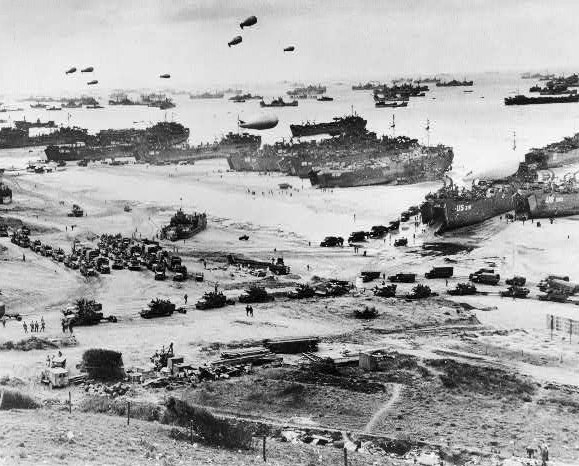 Bird's-eye view of landing craft, barrage balloons, and allied troops landing in Normandy, France on D-Day