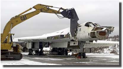 an excavator with giant scissors attached cuts off the nose of a Tu-160 strategic bomber