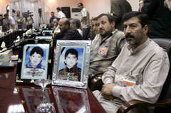 在巴格達什葉派穆斯林居住區的一次汽車炸彈襲擊中喪生的
18名兒童的家人2005年7月在與伊拉克政府官員進行的一次紀念餐會上。桌上是他們孩子
的畫像。