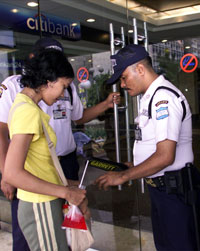 一名安全警衛在雅加達購物中心檢查一位印度尼西亞婦女的
提包。