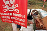 A field worker for a British NGO removes and stores a land mine in Sri Lanka.