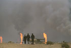 1991年，三名科威特難民迎著地平在線的熊熊油井大火，從伊拉克邊界向家園走去