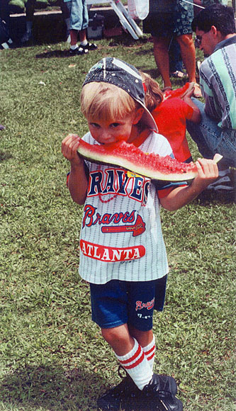 Young boy eating a large piece of watermelon