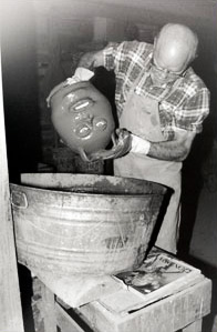 Photo of man dipping jug into bucket