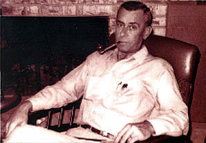 Photo of Max Hunter, sitting in a chair with a pipe