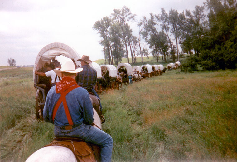 Photo of wagons and riders rounding a bend in the trail