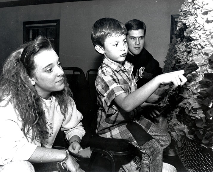 曾就讀於奧克拉荷馬州立大學的父母正在觀看他們的兒子將彩紙塞入花車外的鐵絲內，而這花車是為了參加返校節用的 