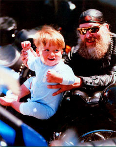 Photo of a biker holding up a young child