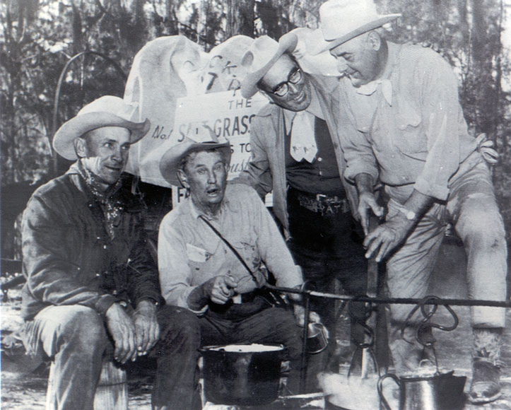 Photo of four men in cowboy hats cooking outside