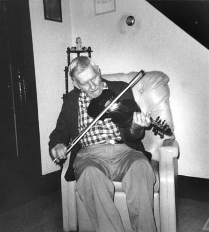 'Henry Reed playing the fiddle in his living room'