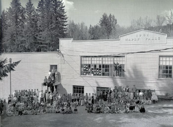 Photo of the front of school with students and teachers posed