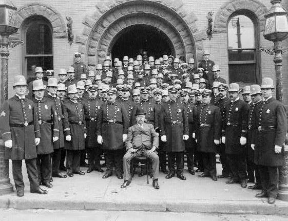 Group of New York City(?) policemen posed in front of police station