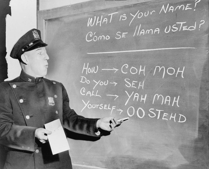 Officer Richard Perry practices basic Spanish phrases using phonetic syllables written on blackboard