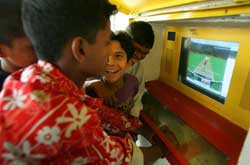 孩子們在"牆上的洞"(Hole in the Wall)項目中心用計算機打板球賽。"牆上的洞"是一個多方合作建立非正式計算機教育項目，其合作方包括美國大使館學校、美國婦女協會(American Women's Association)、一個印度非政府組織和印度國家信息技術學院(National Institute of Information Technology)。