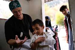 為國際移民組織(IOM)工作的美國專家馬特&middot;喬治(Matt George)在克什米爾用硬紙板為一名男孩固定受傷的手臂。