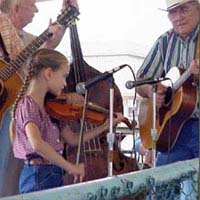 Photo of a young girl playing the fiddle with a two guitarists and a stand-up bass