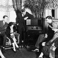 Atwater Kent, standing by radio, and seven other people listening to the radio